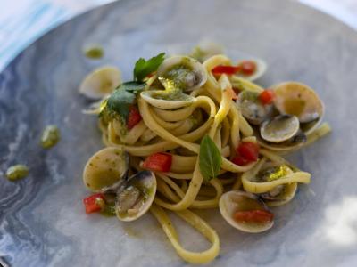Linguine con vongole, pomodori e pesto su piatto elegante.