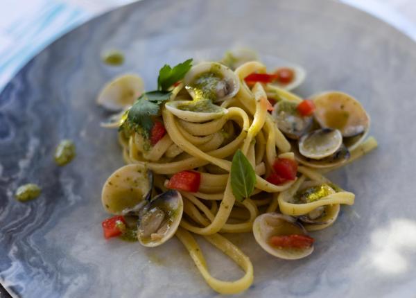 Linguine con vongole, pomodori e pesto su piatto elegante.