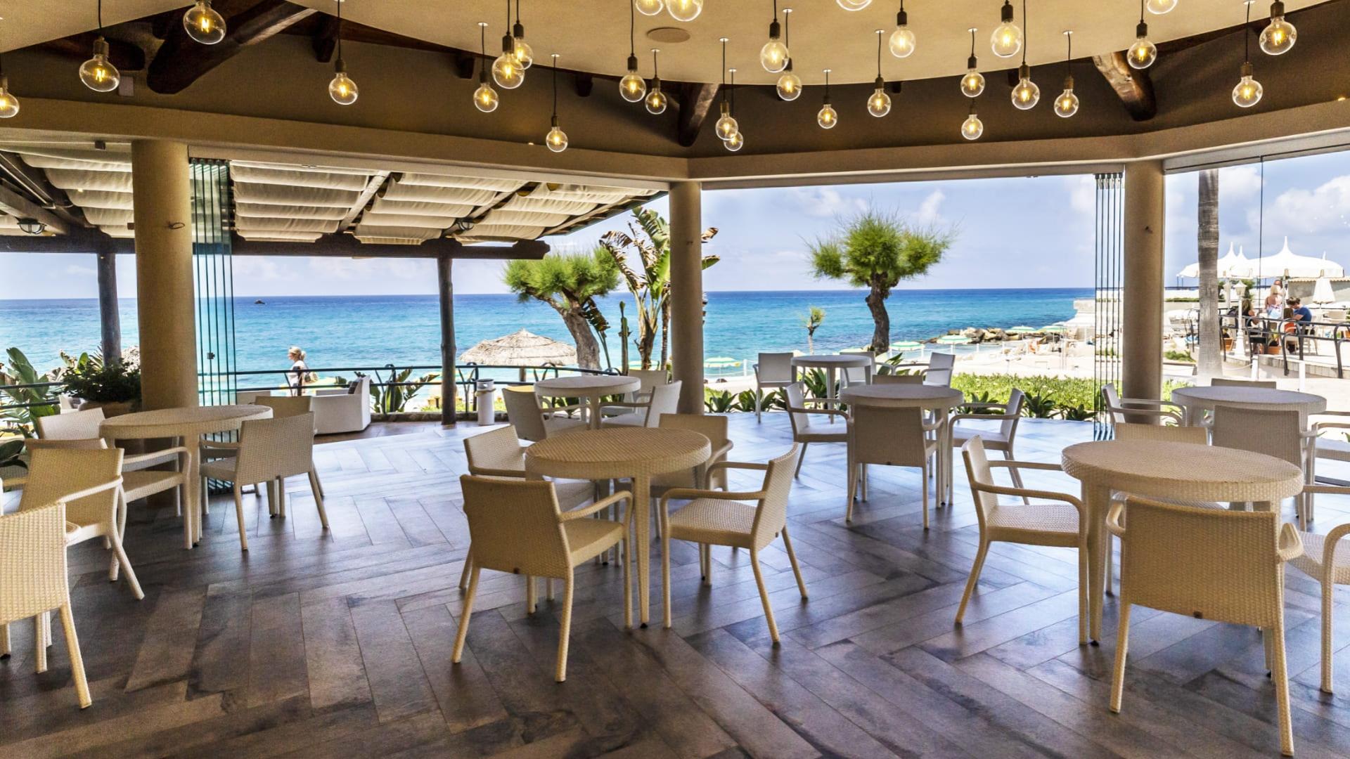 Restaurant am Meer mit moderner Einrichtung und hängenden Lichtern.
